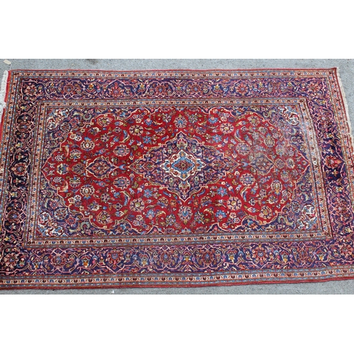 55 - Modern Kashan carpet with a medallion and all-over floral design on a red ground with borders, 9ft 8... 