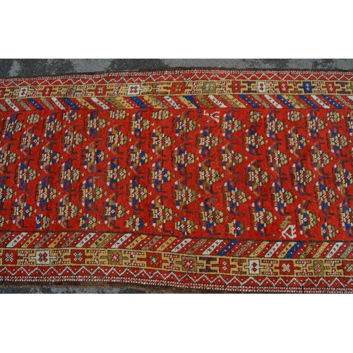 11 - Kazak runner with an all-over stylised flowerhead design on a red ground with borders, 12ft 10ins x ... 