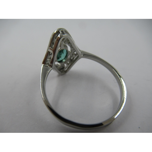 1305 - Platinum ring set single oval emerald surrounded by diamonds in a pierced setting, size N