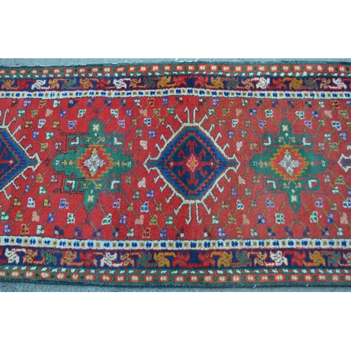 29 - Karaja runner with seven hooked medallions on a brick red ground with borders, 9ft 10ins x 2ft 10ins... 