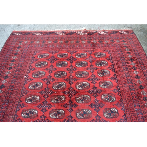 33 - Afghan carpet with rows of nine gols on a wine red ground, with multiple borders, 8ft 8ins x 7ft 8in... 