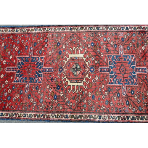 57 - Modern Karaja runner with a seven medallion and all-over floral design on a red ground with narrow b... 