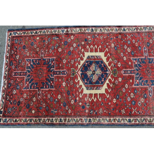 57 - Modern Karaja runner with a seven medallion and all-over floral design on a red ground with narrow b... 