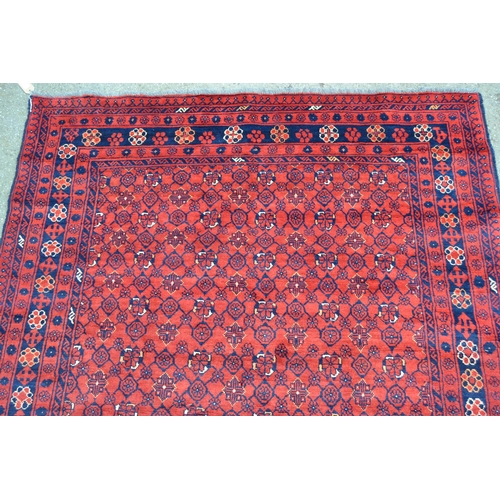 65 - Indo Persian rug of Belouch design with an all-over stylised flower head pattern on a red ground wit... 