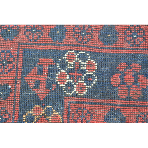 65 - Indo Persian rug of Belouch design with an all-over stylised flower head pattern on a red ground wit... 