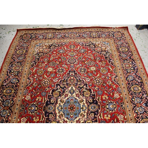 14 - Modern Kashan carpet with a lobed medallion and all-over stylised floral design, on a red ground wit... 