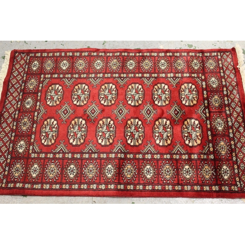 33 - Pakistan Bokhara rug with three rows of gols on a red ground, 189cms x 125cms, together with a simil... 