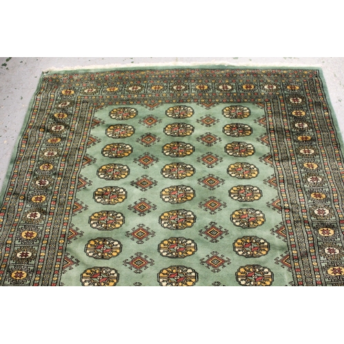 34 - Pakistan Bokhara rug with three rows of gols on a green ground with borders, 253cms x 157cms