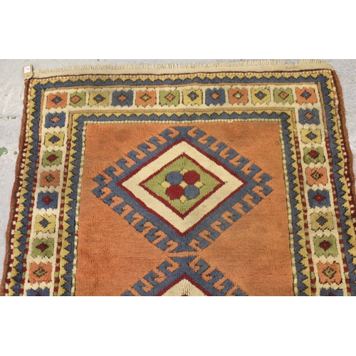 47 - Small Turkish rug with a twin hooked medallion design on a rose ground with borders, 132cms x 108cms