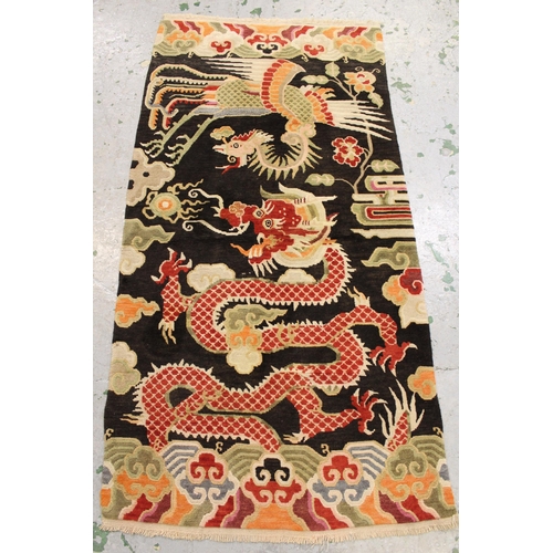 5 - Small Tibetan rug woven with a phoenix and dragon design, on dark ground with cloud pattern end pane... 