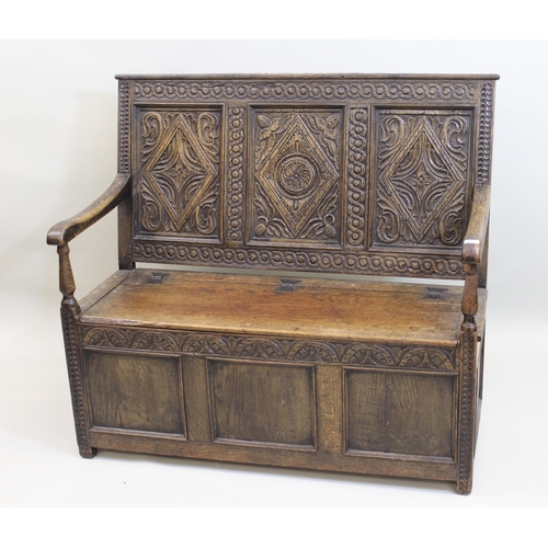 1385 - 19th / early 20th Century oak box settle, the carved three panel back above a hinged seat and three ... 