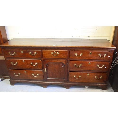 1605 - 18th Century oak dresser base, a moulded plank top above an arrangement of seven drawers with brass ... 