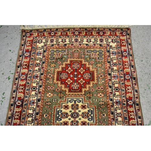 34 - Small Indo Persian rug with a triple medallion design on a green ground with borders, 149cms x 89cms... 