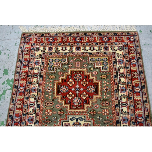 34 - Small Indo Persian rug with a triple medallion design on a green ground with borders, 149cms x 89cms... 