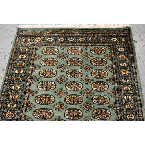 40 - Pakistan rug of Turkoman design with three rows of gols on a green ground with borders, 187cms x 122... 