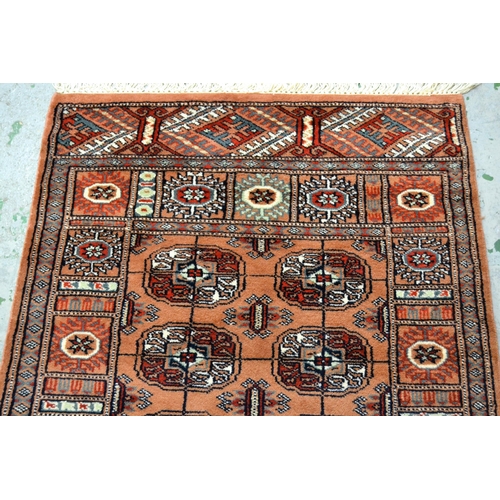 42 - Pakistan rug of Turkoman design with two rows of gols on a pink ground with borders, 147cms x 90cms