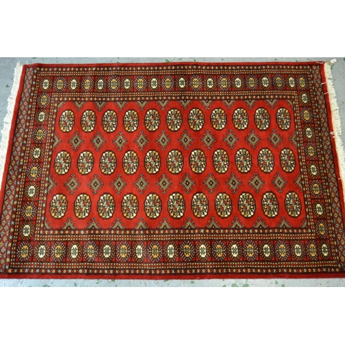 44 - Pakistan rug of Turkoman design with three rows of gols on red ground with borders, 182cms x 124cms