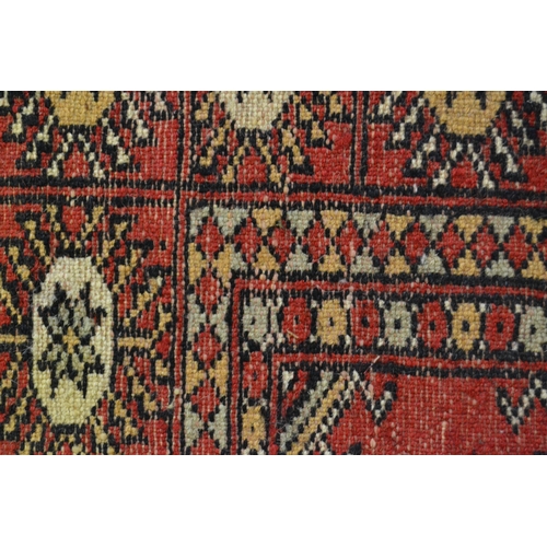 44 - Pakistan rug of Turkoman design with three rows of gols on red ground with borders, 182cms x 124cms