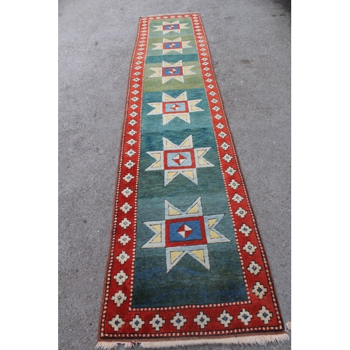 12 - Turkish runner of Kazak design, with green  blue ground and red border, 4metres x 86cms