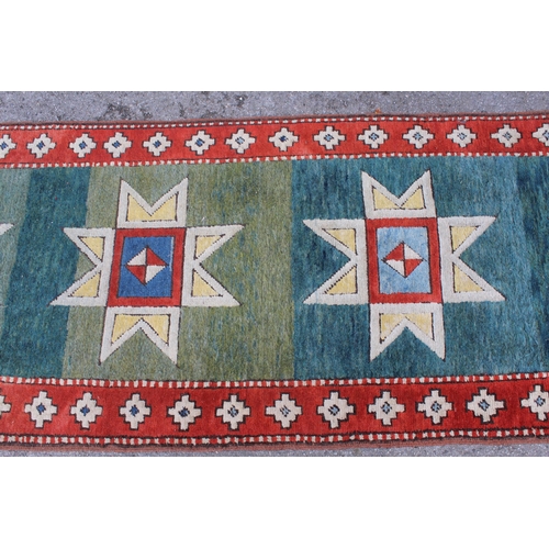 12 - Turkish runner of Kazak design, with green  blue ground and red border, 4metres x 86cms