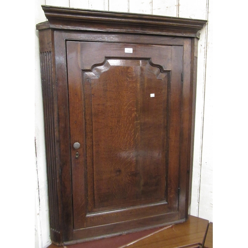 1554 - 18th Century oak hanging corner cabinet, the moulded cornice above an arched fielded panel door encl... 