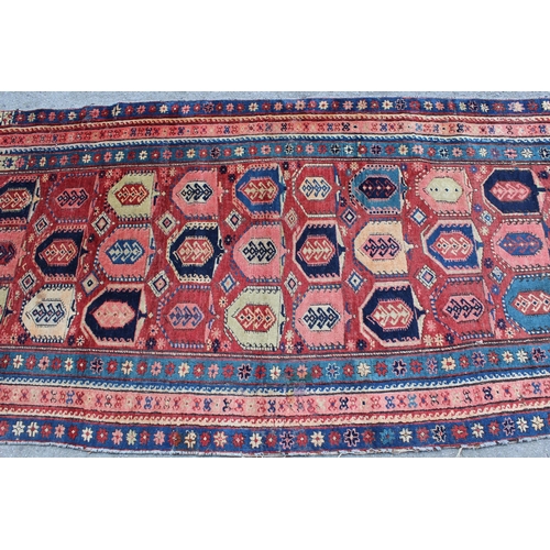 18 - Kazak runner with an all-over stylised design on a brick red ground with borders, 250cms x 108cms ap... 