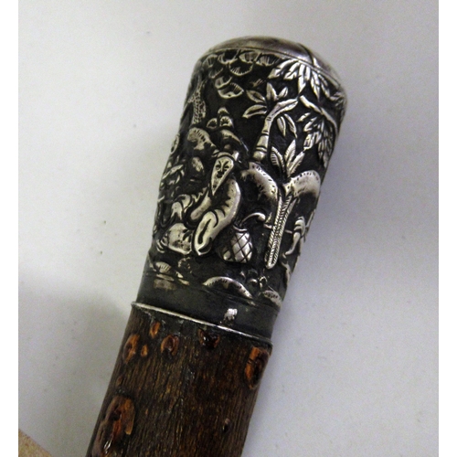 216 - Chinese white metal mounted walking cane, the handle decorated with various figures in a setting wit... 