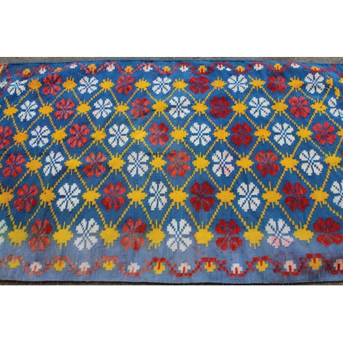 25 - Kelim rug of all-over floral design, on blue ground, 190cms x 104cms