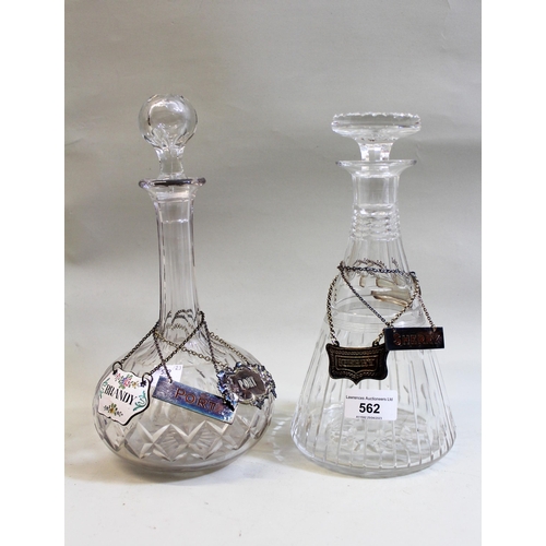 562 - Two cut glass decanters with various labels including a pair of silver Port and Sherry labels, an Ar... 