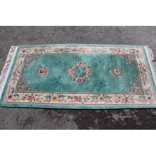 7 - Modern rectangular Chinese rug with all-over floral design and borders on a green ground, 93cms x 11... 