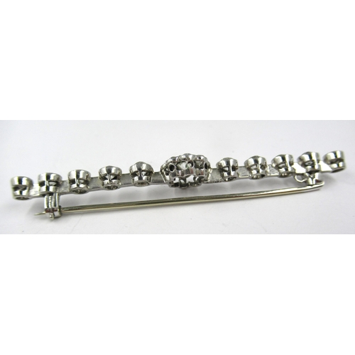 758 - 18ct White gold bar brooch, the centre diamond set flowerhead cluster flanked by ten graduated old b... 