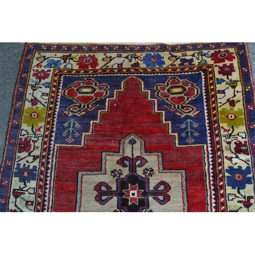 11 - Anatolian rug with a twin medallion design on a red ground with borders, 221cms x 122cms
