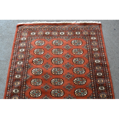 22 - Pakistan rug of Turkoman design with three rows of gols on a rust ground, 185cms x 125cms
