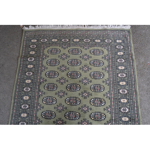 23 - Pakistan rug of Bokhara design with rows of gols on a green ground, 185cms x 123cms (some moth damag... 