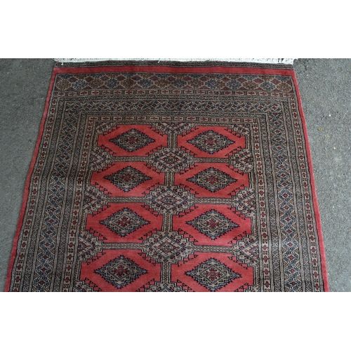 29 - Pakistan rug of Bokhara design with two rows of gols on a rose ground with multiple border, 180cms x... 
