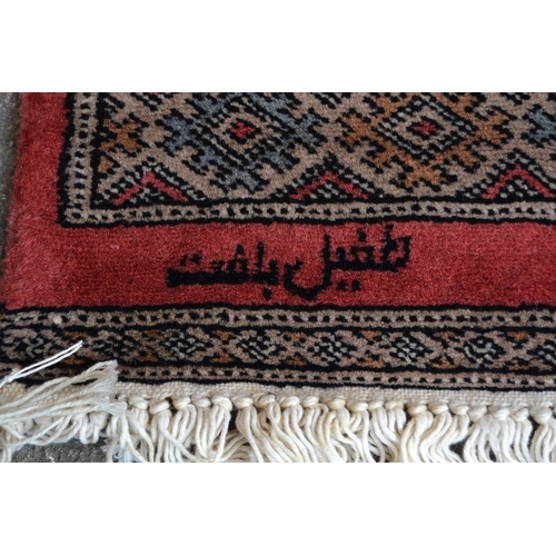 29 - Pakistan rug of Bokhara design with two rows of gols on a rose ground with multiple border, 180cms x... 