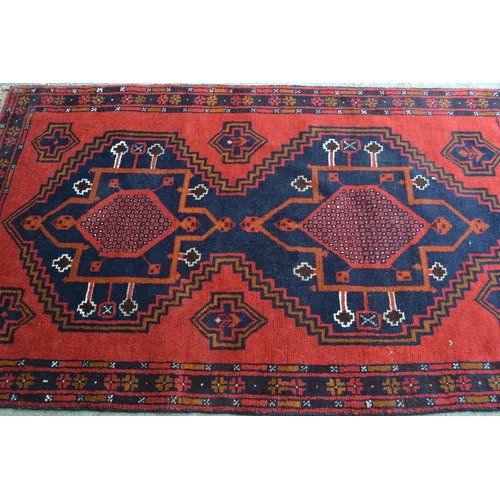 33 - Belouch rug with a triple medallion design in shades of red, blue, brown and orange, 190cms x 115cms