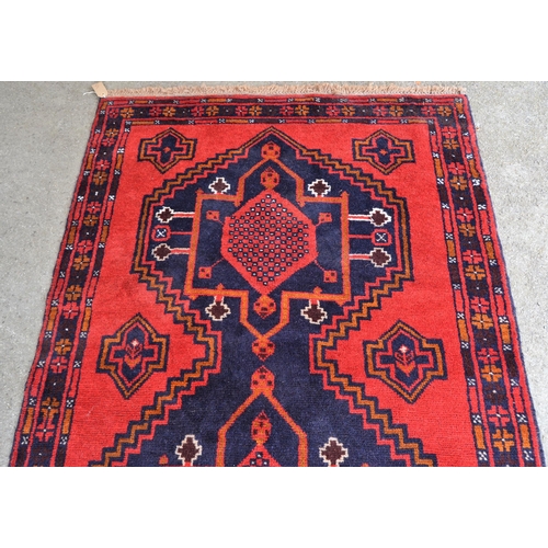 33 - Belouch rug with a triple medallion design in shades of red, blue, brown and orange, 190cms x 115cms