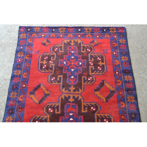 37 - Modern Belouch rug with a twin medallion design in shades of dark blue and red, 190cms x 115cms (som... 