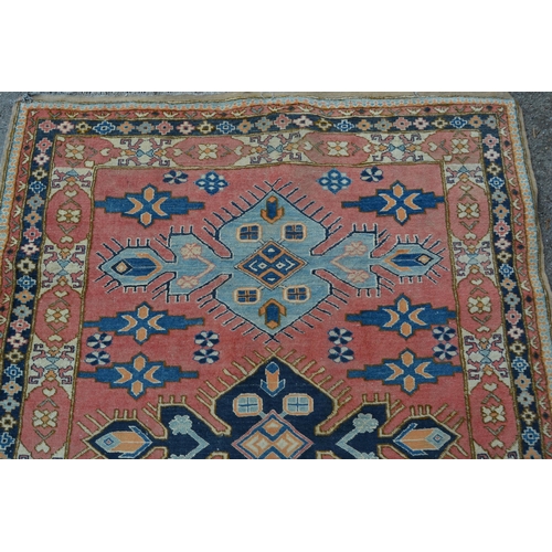 7 - Turkish rug of Caucasian design with triple medallion on a rose ground with borders, 184cms x 145cms