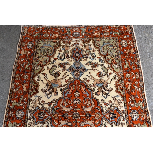 12 - Indo Persian rug with a medallion and hunting design in shades of iron red and cream, 183cms x 122cm... 