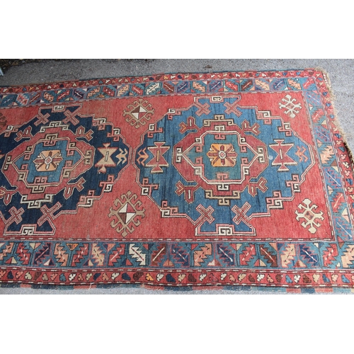 26 - Kurdish rug with a medallion design on a wine ground with borders