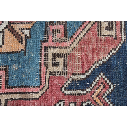 26 - Kurdish rug with a medallion design on a wine ground with borders