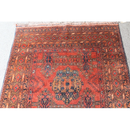 41 - Afghan rug with a twin medallion design on a rust ground with multiple borders, 190cms x 130cms