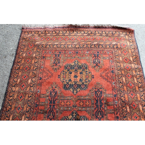 41 - Afghan rug with a twin medallion design on a rust ground with multiple borders, 190cms x 130cms