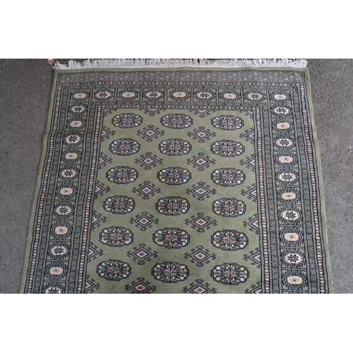 6 - Pakistan rug of Bokhara design with rows of gols on a green ground, 185cms x 123cms (some moth damag... 