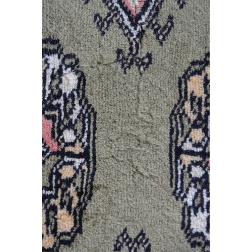 6 - Pakistan rug of Bokhara design with rows of gols on a green ground, 185cms x 123cms (some moth damag... 