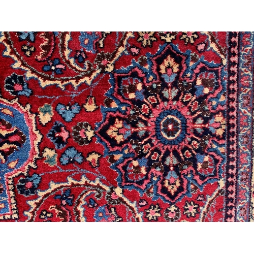 13 - Tabriz carpet with an all-over stylised medallion and floral design on a red ground with palmette bo... 