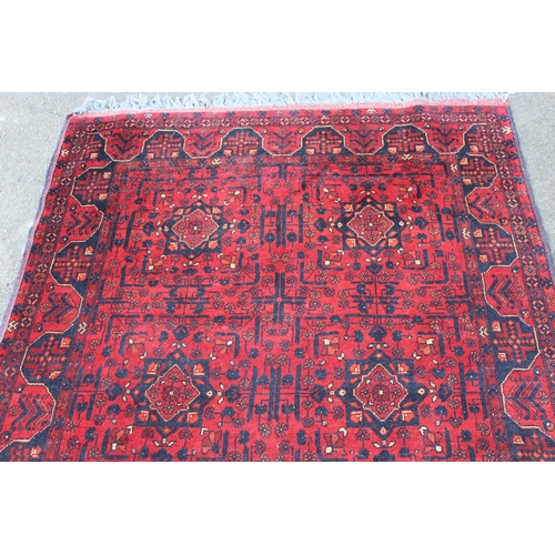 32 - Modern Afghan Belouch rug of six panel design with a dark red ground and borders, 190 x 128cm