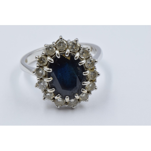 1037 - 18ct White gold oval sapphire and diamond cluster ring, the sapphire approximately 12mm x 10mm, size... 